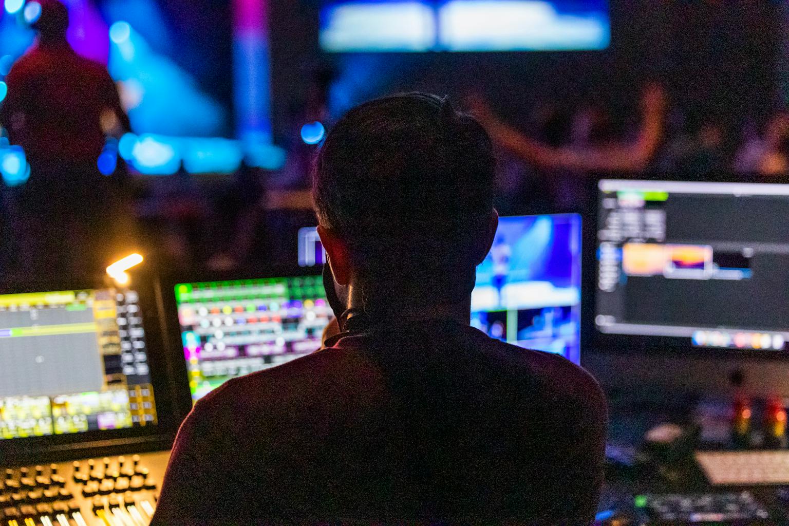 Event producer from behind at the control panel with multiple screens during a live show.